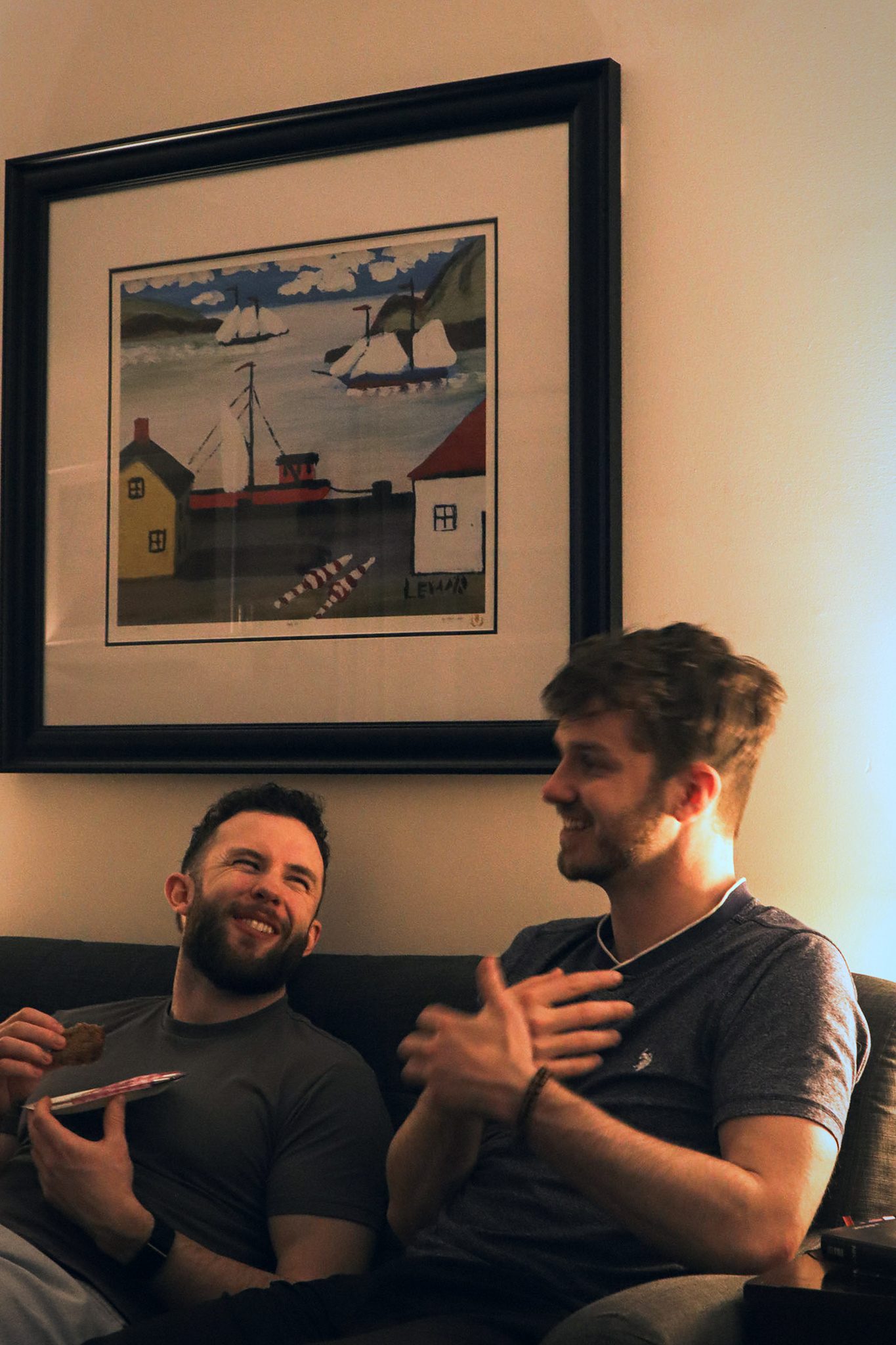 Two men talking and laughing on a couch.
